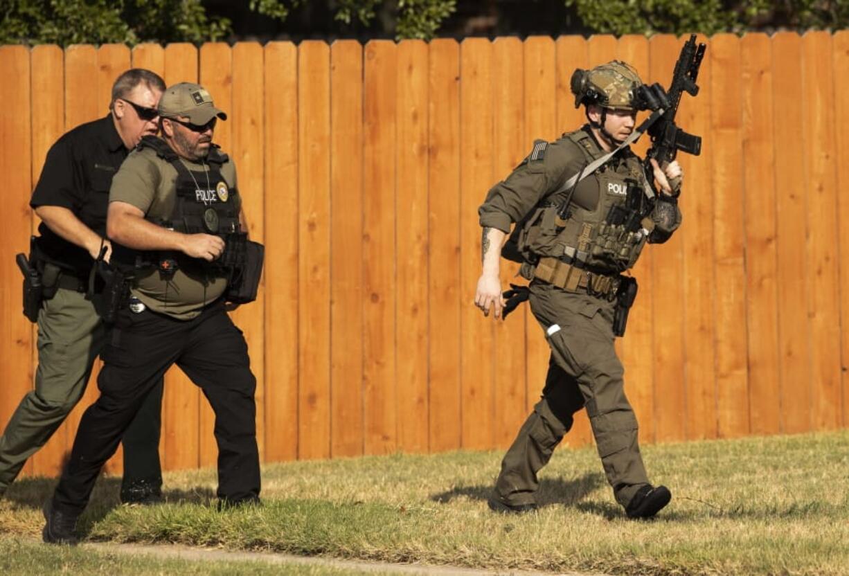 Police officers work near the house in Cedar Park, Texas, where a person remained barricaded Sunday, Aug. 16, 2020. Three police officers were shot, authorities said. The officers are in stable condition at a local hospital, police said on Twitter.