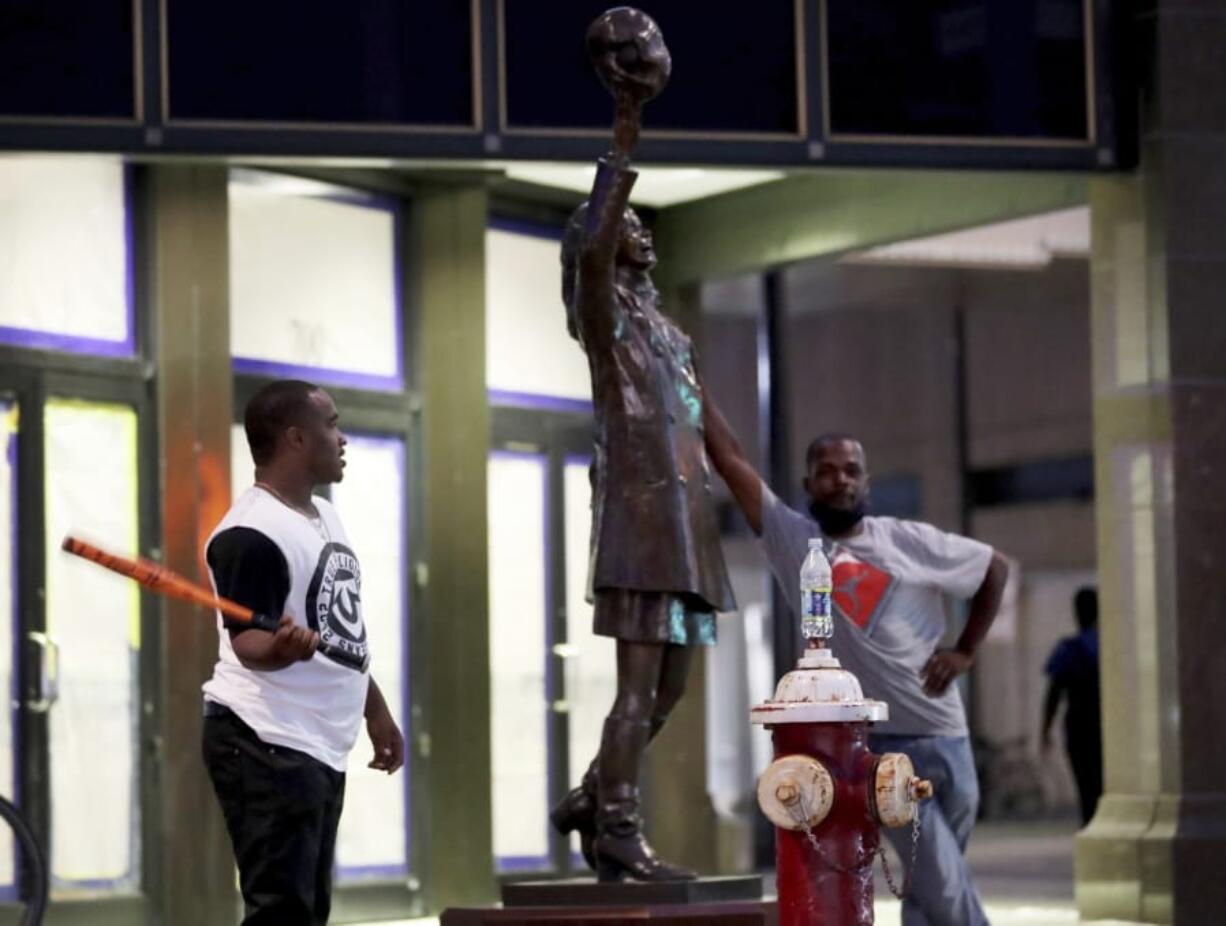 Two men stand by the Mary Tyler Moore statue on Nicollet Mall following a night of unrest in Minneapolis, Thursday, Aug. 27, 2020.  An emergency curfew expired and downtown Minneapolis was calm Thursday morning after a night of unrest that broke out following what authorities said was misinformation about the suicide of a Black homicide suspect.