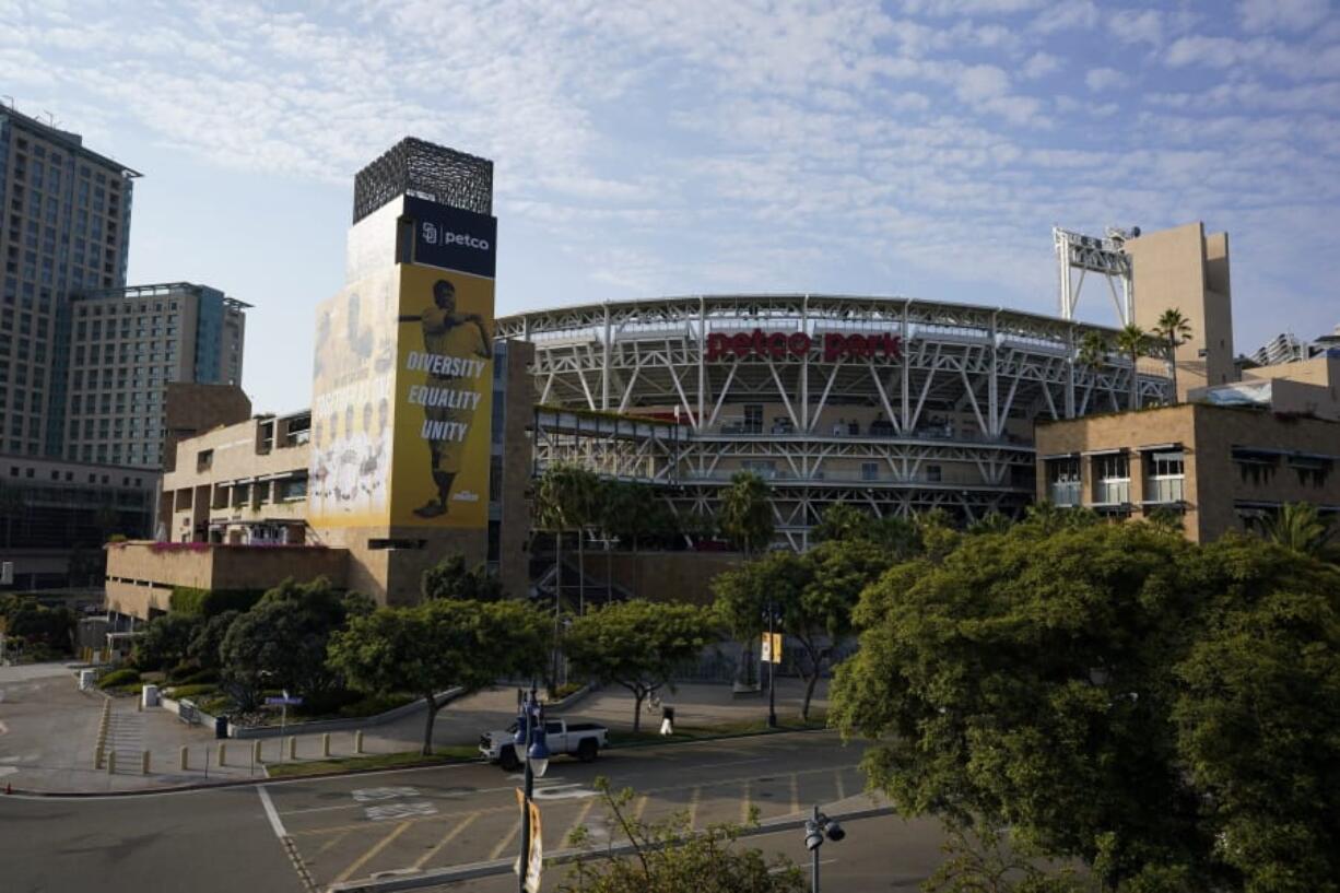 People pass Petco Park, where a baseball game between the San Diego Padres and the Seattle Mariners was scheduled to be played Wednesday, Aug. 26, 2020, in San Diego. Two Major League Baseball games were postponed Wednesday as players across the sports landscape reacted in the wake of the weekend shooting by police of Jacob Blake, a Black man, in Wisconsin. Games between the Cincinnati Reds and Brewers in Milwaukee and the Mariners and Padres in San Diego were called off hours before they were set to begin.