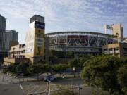 People pass Petco Park, where a baseball game between the San Diego Padres and the Seattle Mariners was scheduled to be played Wednesday, Aug. 26, 2020, in San Diego. Two Major League Baseball games were postponed Wednesday as players across the sports landscape reacted in the wake of the weekend shooting by police of Jacob Blake, a Black man, in Wisconsin. Games between the Cincinnati Reds and Brewers in Milwaukee and the Mariners and Padres in San Diego were called off hours before they were set to begin.