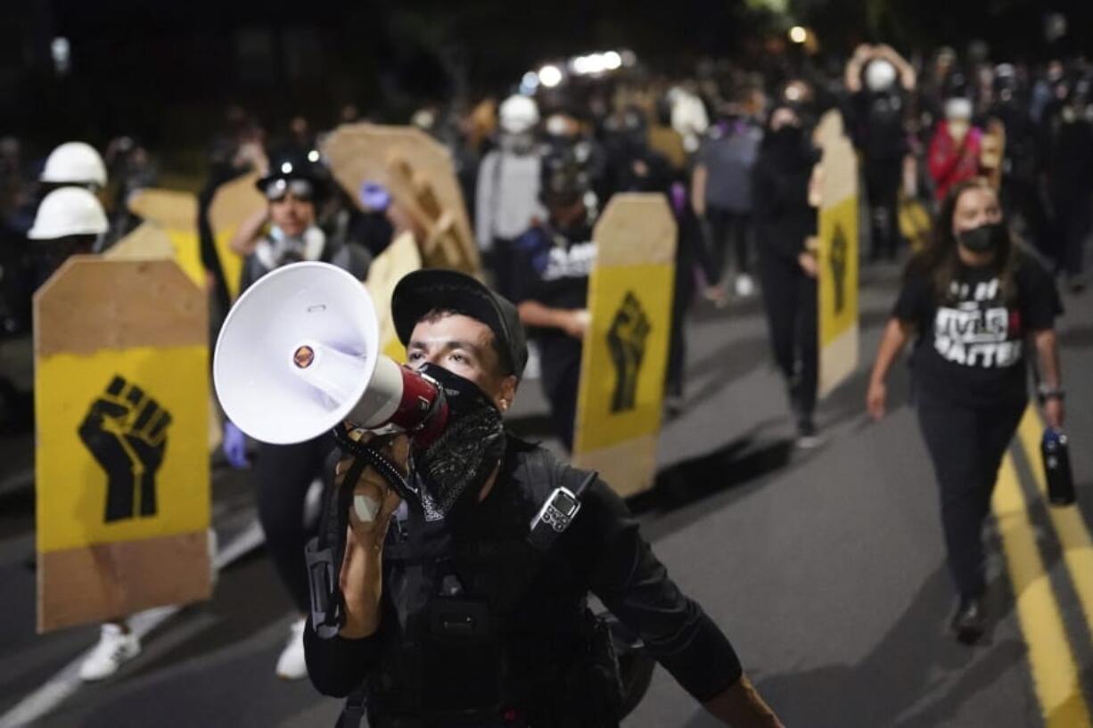 A protester leads a crowd of demonstrators toward the Multnomah County Sheriff&#039;s Office on Saturday, Aug. 7, 2020 in Portland, Ore.