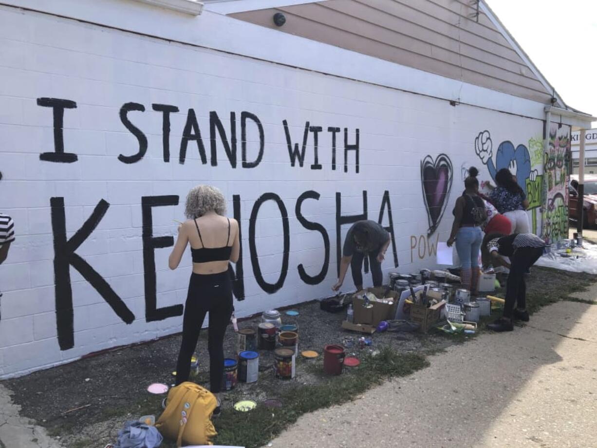 Volunteers paint murals on boarded-up businesses in Kenosha, Wis., on Sunday, Aug. 30, 2020, at an &quot;Uptown Revival.&quot; The event was meant to gather donations for Kenosha residents and help businesses hurt by violent protests that sparked fires across the city following the police shooting of Jacob Blake.