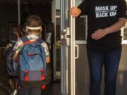 A staff member holds the door open for kids on the first day of school at Goodwin Frazier Elementary School in New Braunfels, Texas on Tuesday, Aug. 25, 2020. The number of Americans newly diagnosed with the coronavirus is falling -- a development experts credit at least partly to increased wearing of masks -- even as the outbreak continues to claim nearly 1,000 lives in the U.S. each day.