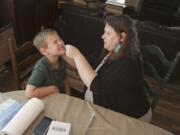 Mendy McNulty swabs the nose of her son, Andrew, 7, Tuesday, July 28, 2020, in their home in Mount Juliet, Tenn. Six thousand U.S. parents and kids are swabbing their noses twice a week to answer some of the most vexing mysteries about the coronavirus. The answers could help determine the safety of in-class education during the pandemic.