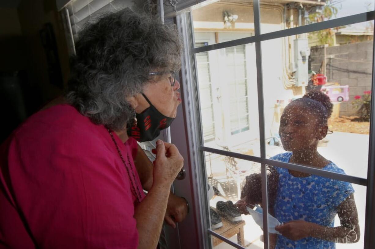 Zita Robinson, 77, blows a kiss to her granddaughter, Traris &quot;Trary&quot; Robinson-Newman, 8, who blows a kiss back to her Aug. 4 in Phoenix. Robinson has been careful around her granddaughter during the pandemic. (ross d.