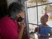 Zita Robinson, 77, blows a kiss to her granddaughter, Traris &quot;Trary&quot; Robinson-Newman, 8, who blows a kiss back to her Aug. 4 in Phoenix. Robinson has been careful around her granddaughter during the pandemic. (ross d.