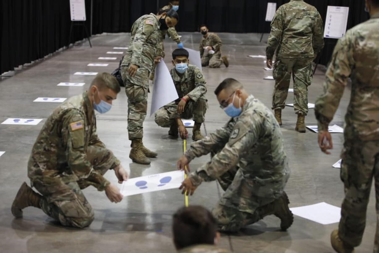 Members of the Nevada National Guard install social distancing stickers while setting up a new temporary coronavirus testing site Monday, Aug. 3, 2020, in Las Vegas.