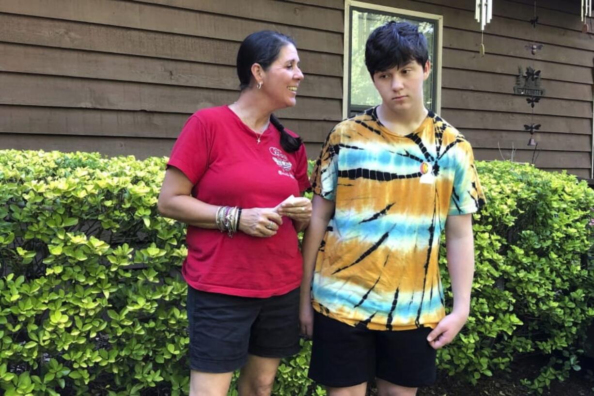 Molly Ball talks to her son Henry about plans to send him back to in-person classes this fall, as they stand outside their house in Woodstock, Ga., Thursday, July 23, 2020. Ball says she thinks Henry and his brother William need the structure and routine of in-person classes, but has regrets about not keeping them home to learn virtually amid the COVID-19 pandemic. Cherokee County, near Atlanta, is one of many districts nationwide that gave parents a choice between in-person and all-online classes this fall.