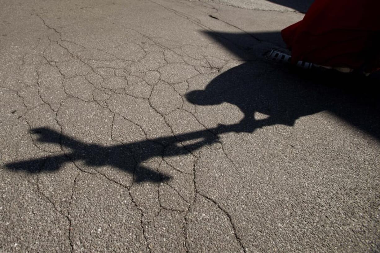 FILE - In this  Friday, April 10, 2020. file photo, the shadow of a priest holding a crucifix is cast on the ground as he leads the Via Crucis, or Way of the Cross ceremony, at the Ospedale di Circolo in Varese, Italy. Two authoritative religious bodies are calling on Christians to band together to fight &quot;sins&quot; laid bare or aggravated by the pandemic, including racism and economic injustice.  The Vatican and the World Council of Churches, which is based in Switzerland, issued a joint document on Thursday, Aug. 27, 2020 asserting that the COVID-19 pandemic &quot;has reminded us of the scandalous gap between the rich and the poor.&quot; The document declared that Christians are compelled to work to heal inequalities, including between men and women.