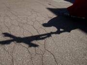 FILE - In this  Friday, April 10, 2020. file photo, the shadow of a priest holding a crucifix is cast on the ground as he leads the Via Crucis, or Way of the Cross ceremony, at the Ospedale di Circolo in Varese, Italy. Two authoritative religious bodies are calling on Christians to band together to fight &quot;sins&quot; laid bare or aggravated by the pandemic, including racism and economic injustice.  The Vatican and the World Council of Churches, which is based in Switzerland, issued a joint document on Thursday, Aug. 27, 2020 asserting that the COVID-19 pandemic &quot;has reminded us of the scandalous gap between the rich and the poor.&quot; The document declared that Christians are compelled to work to heal inequalities, including between men and women.