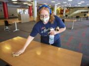 Custodial supervisor Leila Ruiz sanitizes a table in a lounge at the Compton Union Building on Friday, Aug. 28, 2020, at Washington State University in Pullman, Wash. Tables in the building are being sanitized once an hour. The university has launched the Cougs Cancel COVID campaign after a surge in the number of students testing positive for COVID-19 this week.