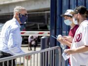 MLB Commissioner Rob Manfred, left, speaks with fans as he arrives at Nationals Park for the New York Yankees and the Washington Nationals opening day baseball game, Thursday, July 23, 2020, in Washington.