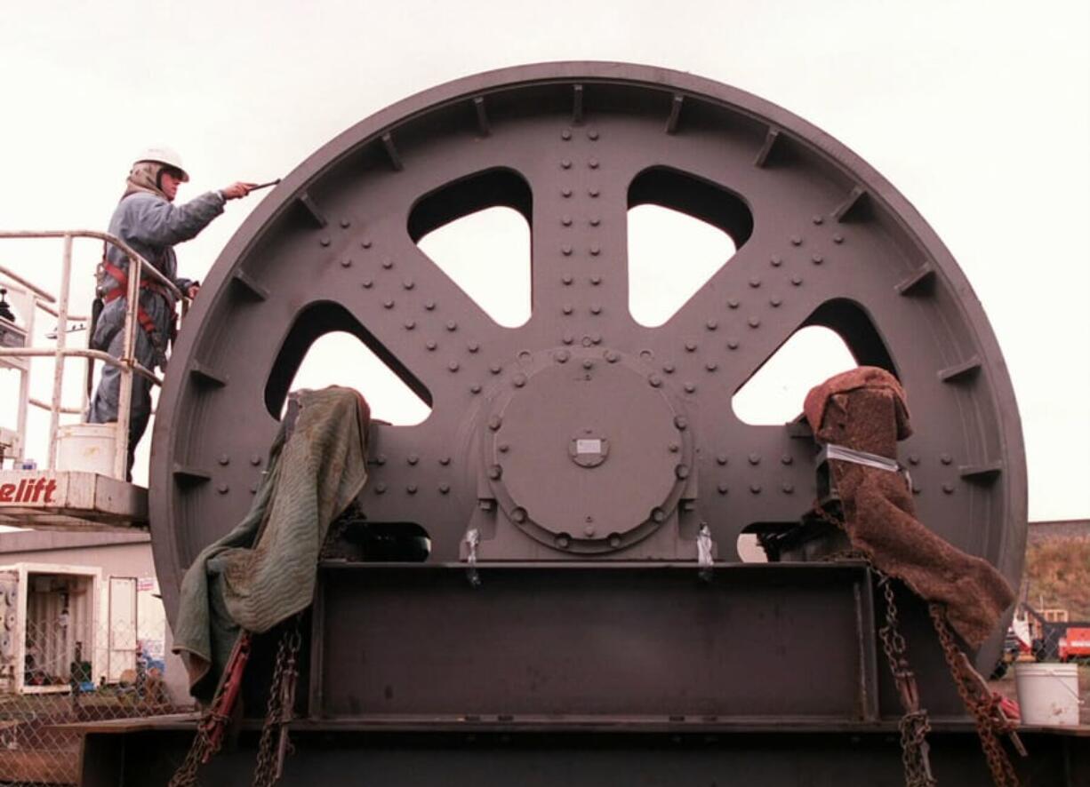 An employee from Long Painting Co. from Portland removed metal protectant and applied a light coat of grease to the a lift span counterweight sheave that was being installed atop the Interstate 5 Bridge in 1997.