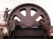 An employee from Long Painting Co. from Portland removed metal protectant and applied a light coat of grease to the a lift span counterweight sheave that was being installed atop the Interstate 5 Bridge in 1997.