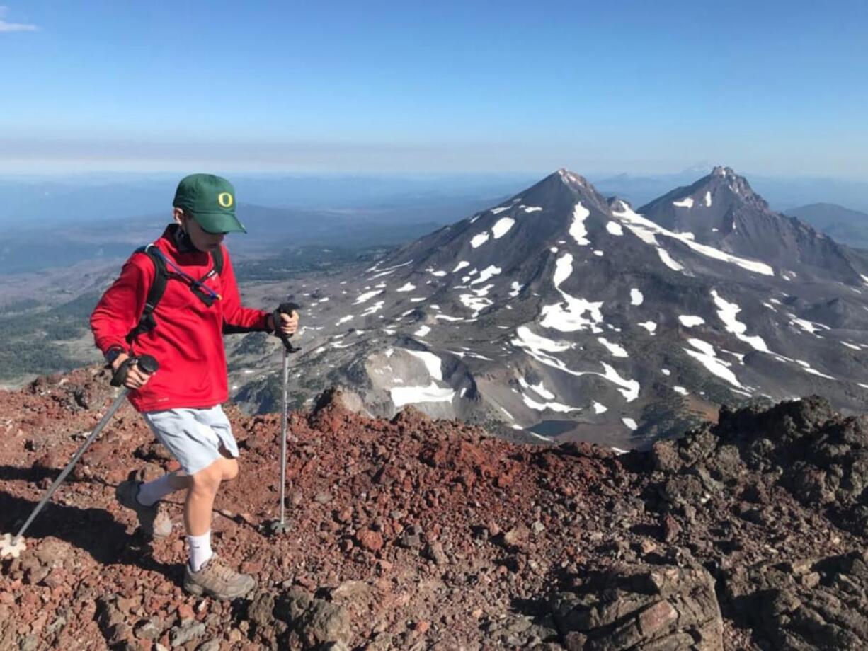 Mason Morical, 12, of Bend, Ore., walks across the summit of South Sister on Aug. 15. In the background, Middle Sister, left, and North Sister, right, can be seen from the summit.