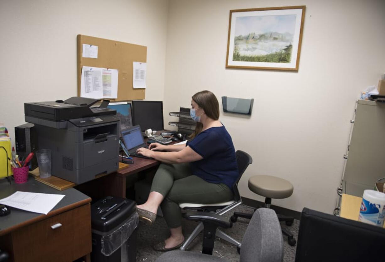 Medical student Megan Short works with a patient while communicating via smartphone during a telemedicine clinic at the Vancouver-based Free Clinic of Southwest Washington in August. The clinic brought back in-person appointments this month.