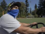 Roy Flores, a grounds maintenance specialist at Luke Jensen Sports Park, steps behind the wheel as he prepares to sweep a soccer field on a recent weekday.