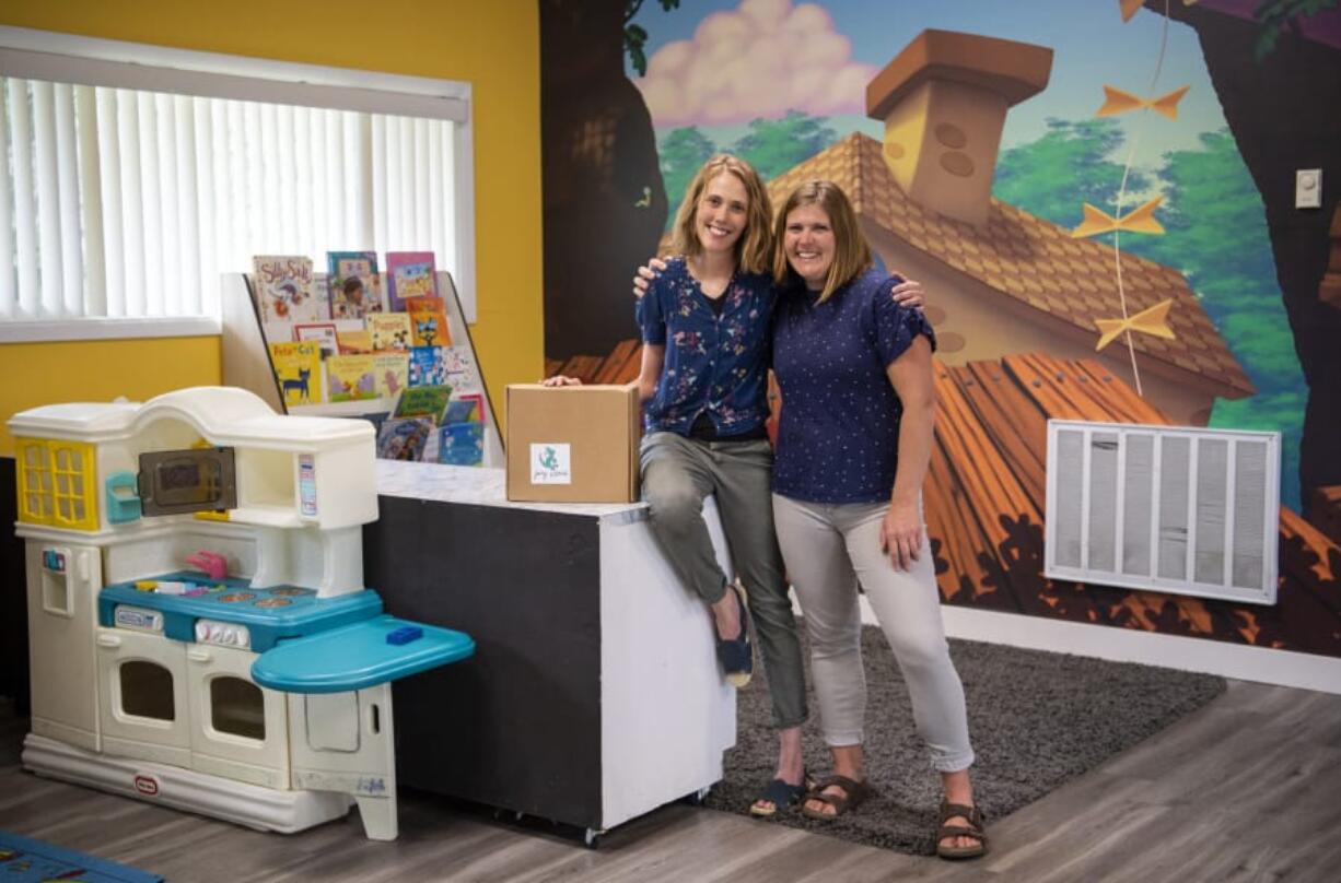 Melanie Hanes and KT Tidwell show off the different items in the Joey School subscription boxes at their Sprouts Academy day care in Ridgefield on Monday morning. The boxes come with various educational activities for parents to complete with their kids.