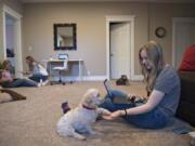 Eighth grader Taryn Albrecht, 13, left, gears up for the first day of school with help from her sister, Nina, 17, who is a senior, while their other sister, Kira, 15, who is a sophomore, shares a moment with their dog, Charlie, 8, at their Vancouver home Tuesday morning. Classes continued to be held online as concerns about COVID-19 shut down schools.