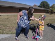 Kindergarten teacher Miranda Roderick, left, greets kindergartner Avery Anderson, 5, as she cruises by River HomeLink with her family to pick up materials for the upcoming school year. Enrollment in Alternative Learning Experiences, such as River HomeLink, is up while school districts operate remotely.