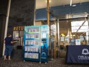 Deborah Carter of Vancouver returns books next to the Little Lending Library, a machine that allows visitors to browse a small selection of books while the Vancouver Mall library branch remains closed due to the coronavirus pandemic.