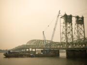 The northbound span of the Interstate 5 Bridge will close to all traffic for nine days beginning Saturday. All freeway traffic will use the southbound span while crews work to replace a cracked trunnion and other parts of the northbound bridge&#039;s lift system. At top: Crews will use a barge-mounted crane to lift down the worn-out components of the lift system and replace them with new parts.