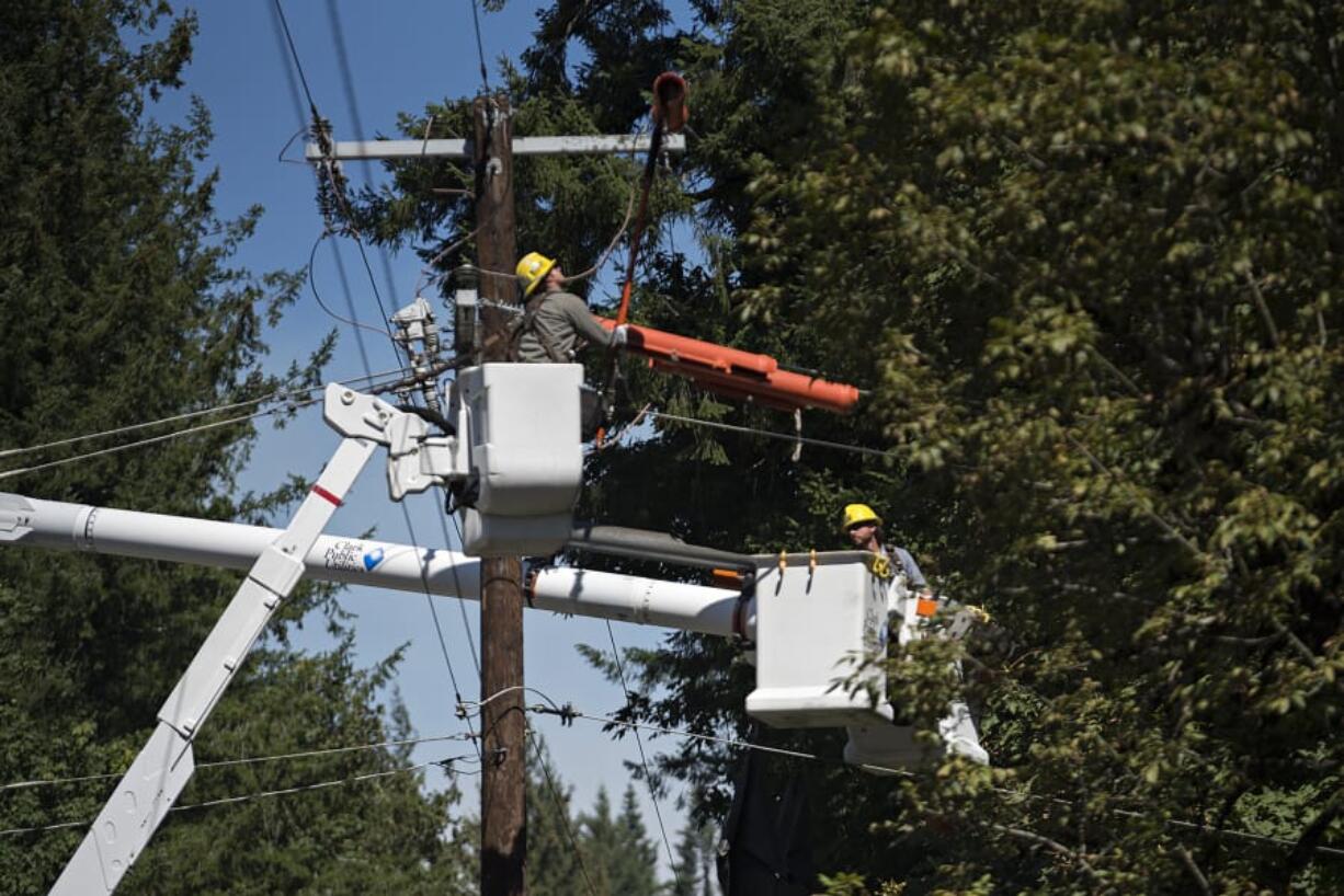 Derek Shaffer, left, of Clark Public Utilities works with colleague Tony Kutzera as they restore power to residents along Lewisville Highway near Northeast Gabriel Road on Tuesday afternoon.