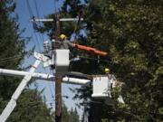 Derek Shaffer, left, of Clark Public Utilities works with colleague Tony Kutzera as they restore power to residents along Lewisville Highway near Northeast Gabriel Road on Tuesday afternoon.