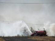 A water tender is put to use fighting a brush fire off Fruit Valley Road and Northwest Lower River Road late Tuesday afternoon.