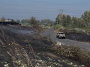 A motorist drives past burned areas on both sides of the road in Shilapoo Wildlife Area off La Frambois Road on Wednesday morning, Sept. 9, 2020.