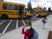 Kindergartner Evalynn Pratt, 5, secures her face mask while waiting for her classmates to arrive on the bus at Sifton Elementary School in September.