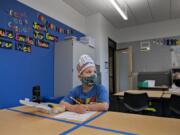 Kindergartner Phoenix Winmil, 5, wears a hat that says &quot;I Love Kindergarten&quot; as he tackles schoolwork on the second day of classes at Sifton Elementary School on Tuesday afternoon. Students are isolated to their own table rather than the typical arrangement of four students to one large desk. Students are also given their own sets of supplies that can be disinfected after class is over.