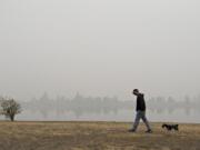 Vancouver resident Frank Schmit wears a mask while taking his dog, Ripley, a miniature schnauzer, for a stroll as thick wildfire smoke obscures the visibility of trees across the water at Frenchman' Bar Regional Park. Schmit said the fires and the smoke are just the latest in a list of unusual events that have happened in 2020. "It's been a hell of a year," he said.