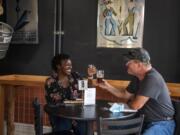 Bella Roushall, left, and her husband, Scott, enjoy beers together Saturday at Trusty Brewing in Vancouver.