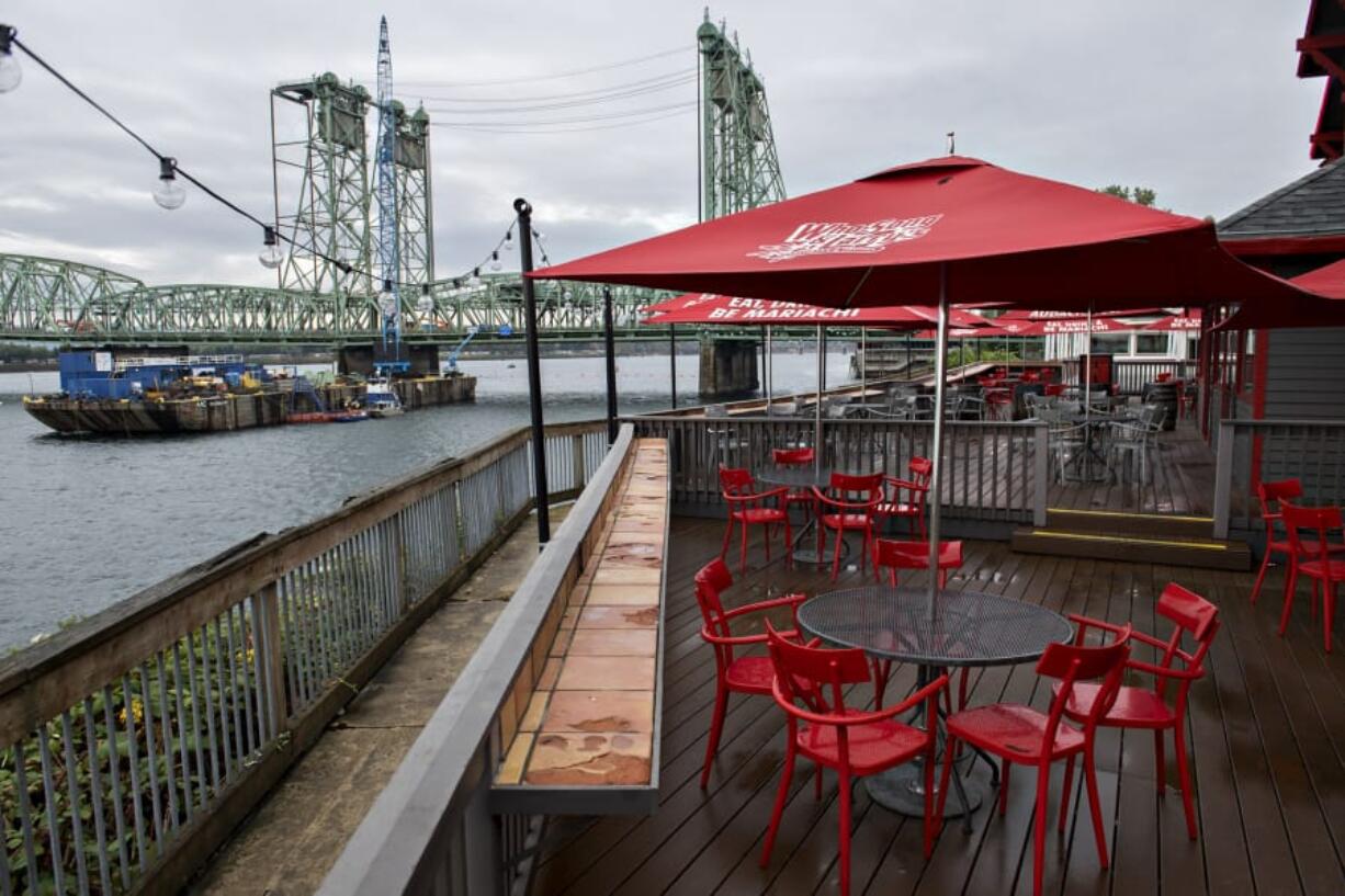 Work continues on the Interstate 5 Bridge during the trunnion replacement project, seen from the outdoor seating area at Who Song &amp; Larry&#039;s. Across the river at Jantzen Beach, restaurant owners say that business is down by roughly 50 percent because the bridge project is stopping patrons driving from Washington.