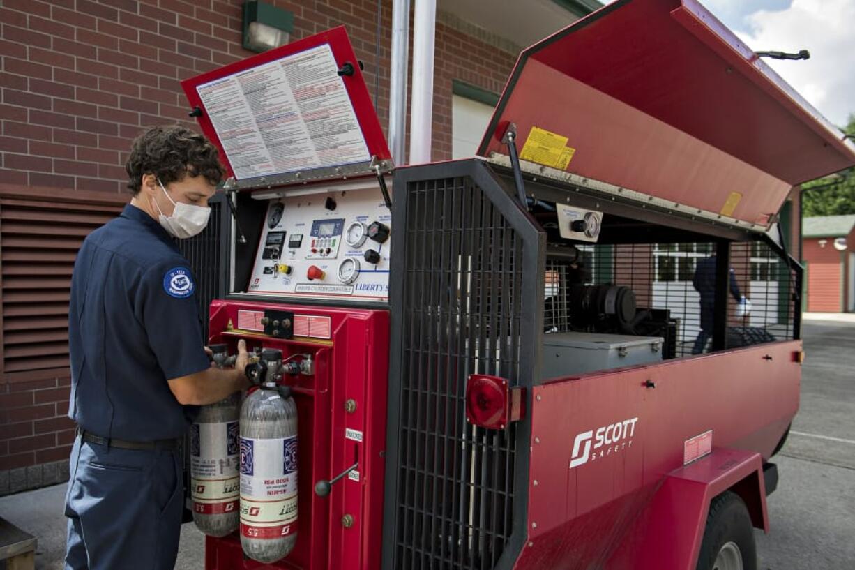 Firefighter Michael Guinett refills oxygen tanks used by fire crews in smoky situations at Station 31 in Hockinson.