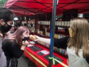 Bailey Dick, 15, offers sniffs of a pumpkin-scented candle to customers Derek Klein and Madilyn Ramey at the Farm Maid booth at the Vancouver Farmers Market on Saturday.