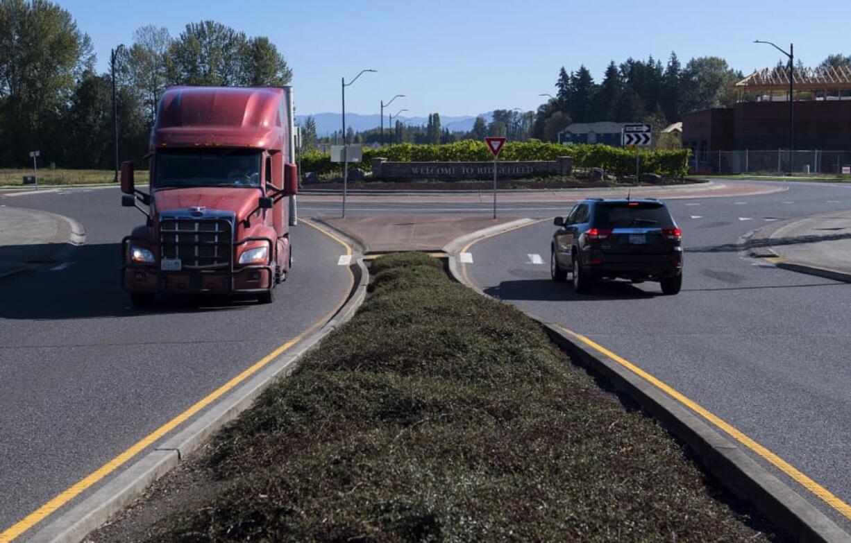 Drivers of a truck and an SUV navigate a roundabout east of Interstate 5 along South Pioneer Street in Ridgefield on Tuesday morning. Below, a motorist passes construction in Ridgefield near the intersection of South Fifth Street and Union Ridge Parkway, which is not part of the grant project but will connect to it, on Tuesday morning.