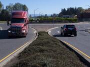 Drivers of a truck and an SUV navigate a roundabout east of Interstate 5 along South Pioneer Street in Ridgefield on Tuesday morning. Below, a motorist passes construction in Ridgefield near the intersection of South Fifth Street and Union Ridge Parkway, which is not part of the grant project but will connect to it, on Tuesday morning.