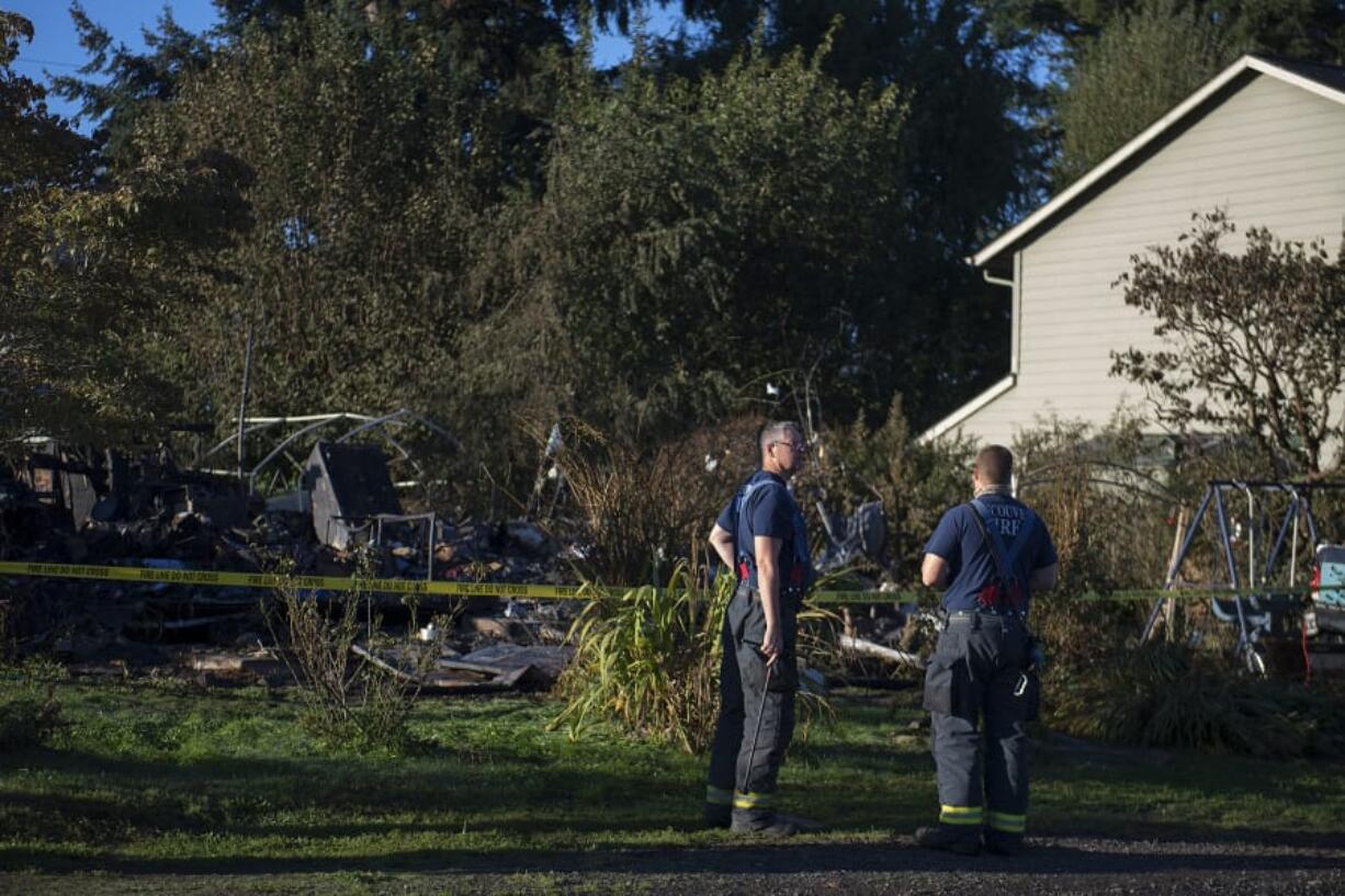 Firefighters look over the charred remains of a house that was destroyed by fire at 1101 W. 19th St., in Vancouver's Hough neighborhood, as seen Tuesday morning. Alan McCall, 59, of Vancouver was arrested after allegedly setting his own house on fire Monday afternoon. His family said he suffers from undiagnosed mental health problems, and they've been unable to get him help.