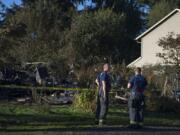 Firefighters look over the charred remains of a house that was destroyed by fire at 1101 W. 19th St., in Vancouver's Hough neighborhood, as seen Tuesday morning. Alan McCall, 59, of Vancouver was arrested after allegedly setting his own house on fire Monday afternoon. His family said he suffers from undiagnosed mental health problems, and they've been unable to get him help.