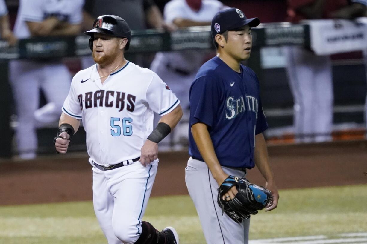 Arizona Diamondbacks' Kole Calhoun (56) scores on a base hit by teammate Nick Ahmed as Seattle Mariners pitcher Yusei Kikuchi (18) watches the play during the first inning of a baseball game, Friday, Sept. 11, 2020, in Phoenix.