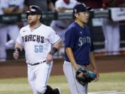 Arizona Diamondbacks' Kole Calhoun (56) scores on a base hit by teammate Nick Ahmed as Seattle Mariners pitcher Yusei Kikuchi (18) watches the play during the first inning of a baseball game, Friday, Sept. 11, 2020, in Phoenix.