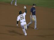 Oakland Athletics' Mark Canha (20) celebrates after hitting a game winning home run, while running past Seattle Mariners' Evan White during the 10th inning of a baseball game in Oakland, Calif., Friday, Sept. 25, 2020.