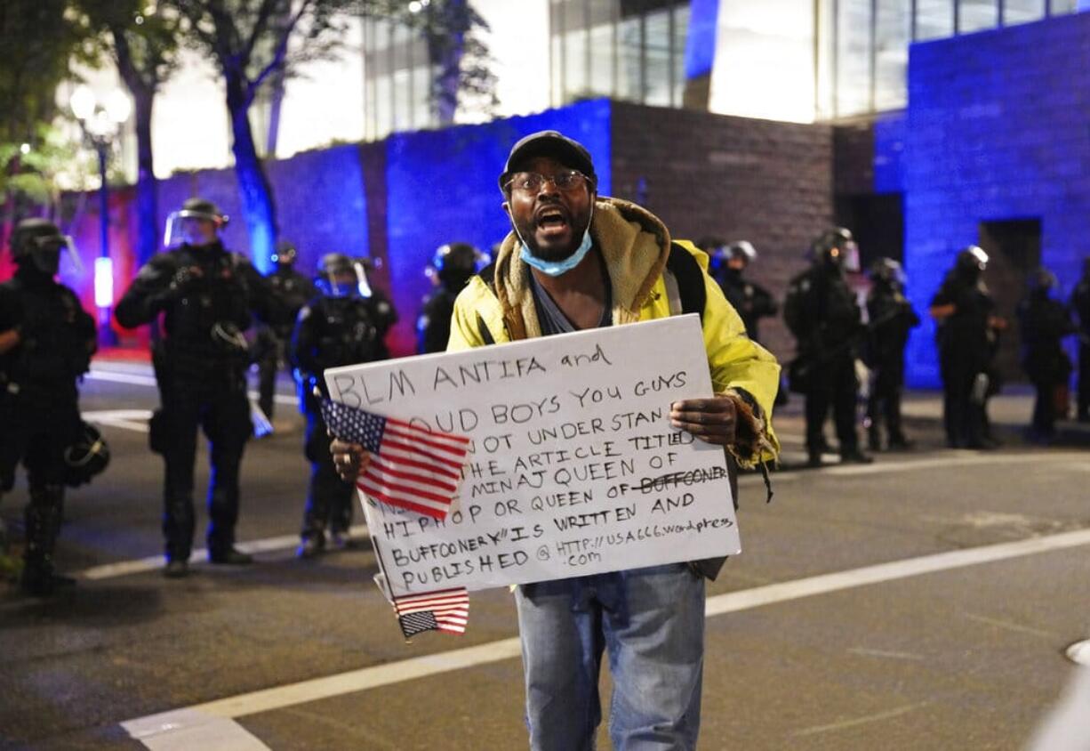 A protester holds a sign while rallying at the Mark O. Hatfield United States Courthouse on Saturday, Sept. 26, 2020, in Portland, Ore.