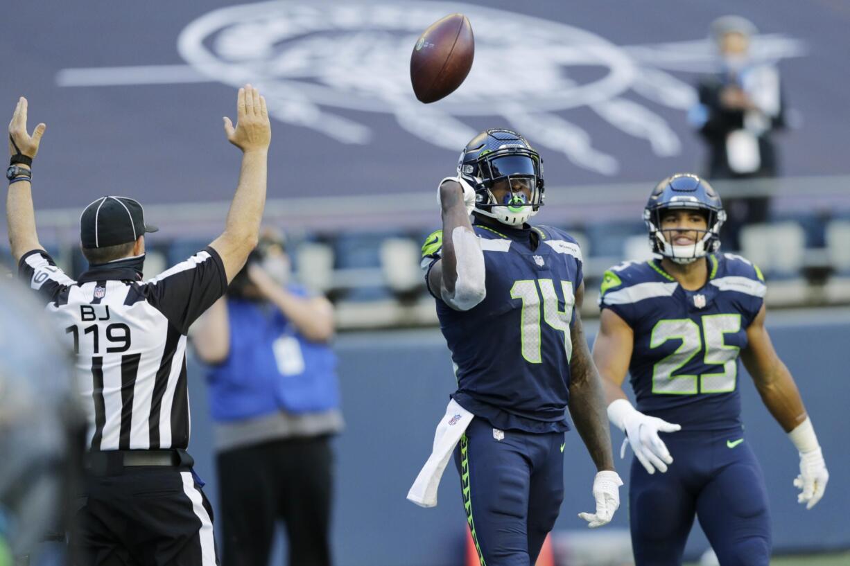 Seattle Seahawks wide receiver DK Metcalf (14) tosses the ball as he stands with running back Travis Homer (25) after Metcalf scored a touchdown against the Dallas Cowboys during the second half of an NFL football game, Sunday, Sept. 27, 2020, in Seattle.