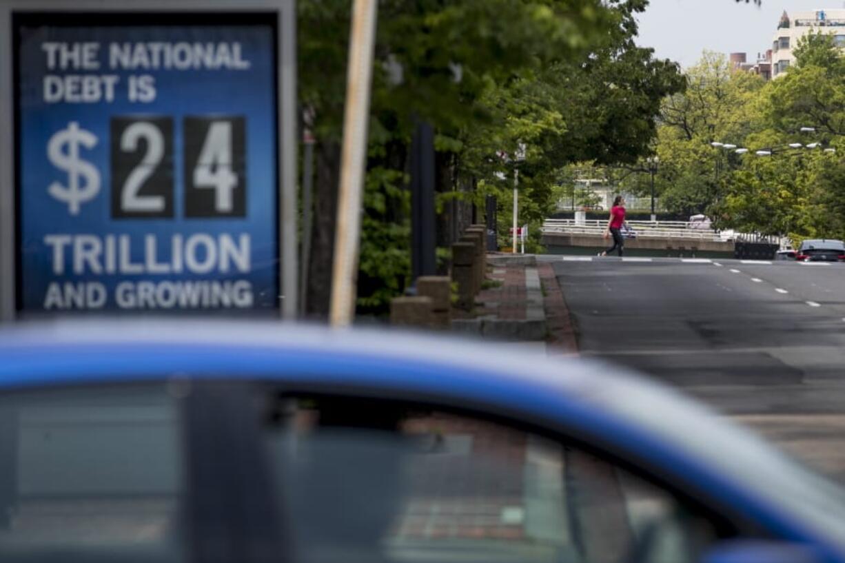 FILE - In this April 29, 2020 file photo, a sign displaying the size of the national debt is displayed along an empty K Street in Washington.  The Congressional Budget Office has warned that the government this year will run the largest budget deficit, as a share of the economy, since 1945, the year World War II ended. Next year, the federal debt -- made up of the year-after-year gush of annual deficits -- is forecast to exceed the size of the entire American economy for the first time since 1946.