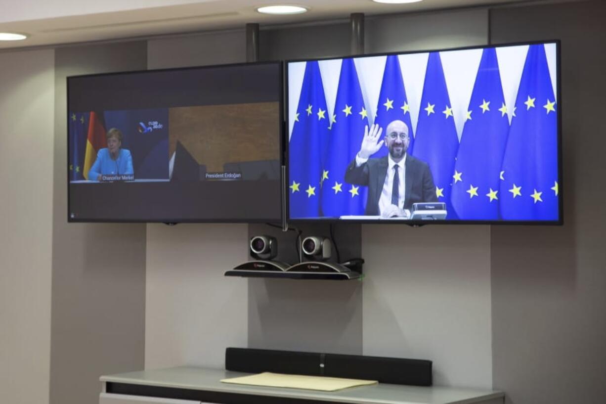 European Council President Charles Michel, screen right, waves as he attends a video conference with German Chancellor Angela Merkel, screen left, and Turkish President Recep Tayyip Erdogan at the European Council building in Brussels, Tuesday, Sept. 22, 2020.