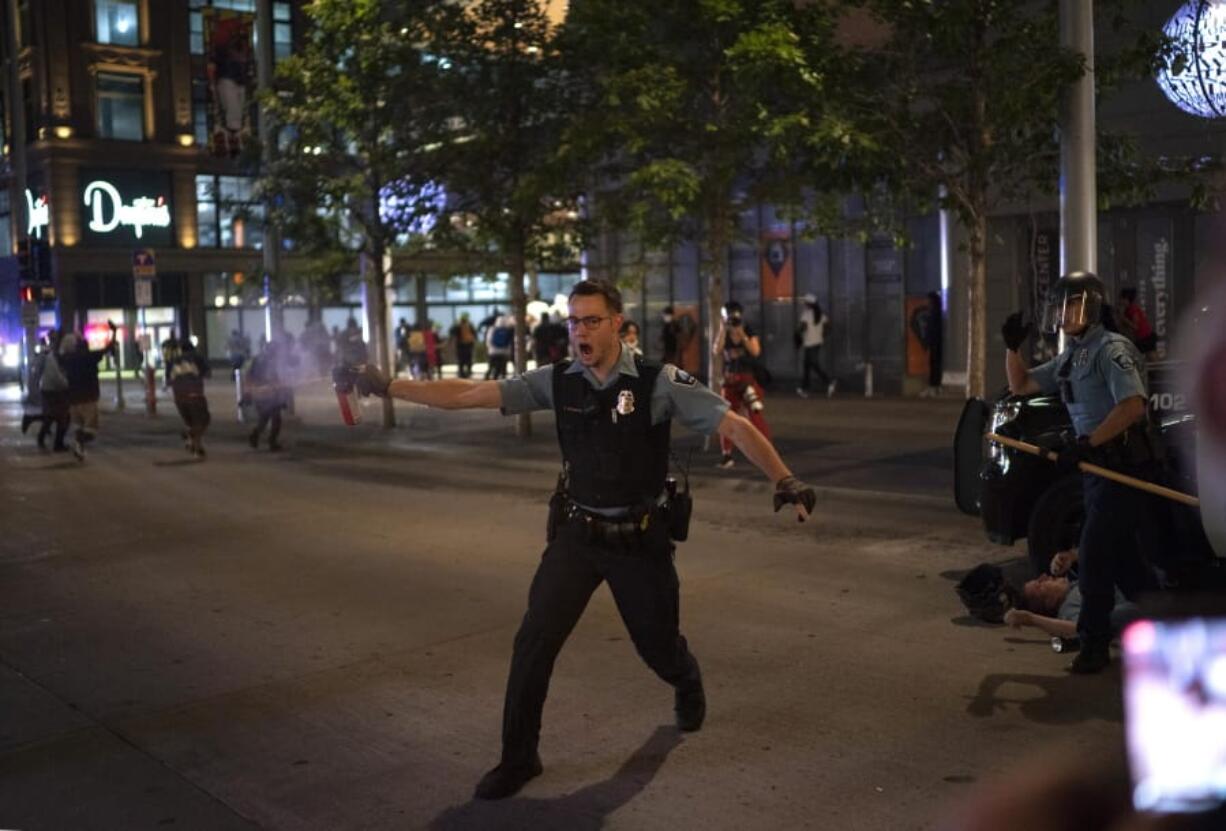 FILE - In this Aug. 26, 2020, file photo, police spray a substance to clear the area where a colleague was down on the Nicollet Mall in Minneapolis. Two men from Minnesota and North Carolina who prosecutors say are members of an anti-government extremist group have been charged with terrorism counts for allegedly building weapons they believed were going to Hamas. They are allegedly members of the &quot;Boogaloo Bois.&quot; The investigation into the men began after they posted messages on social media about inciting violence after the May 25 death of George Floyd.