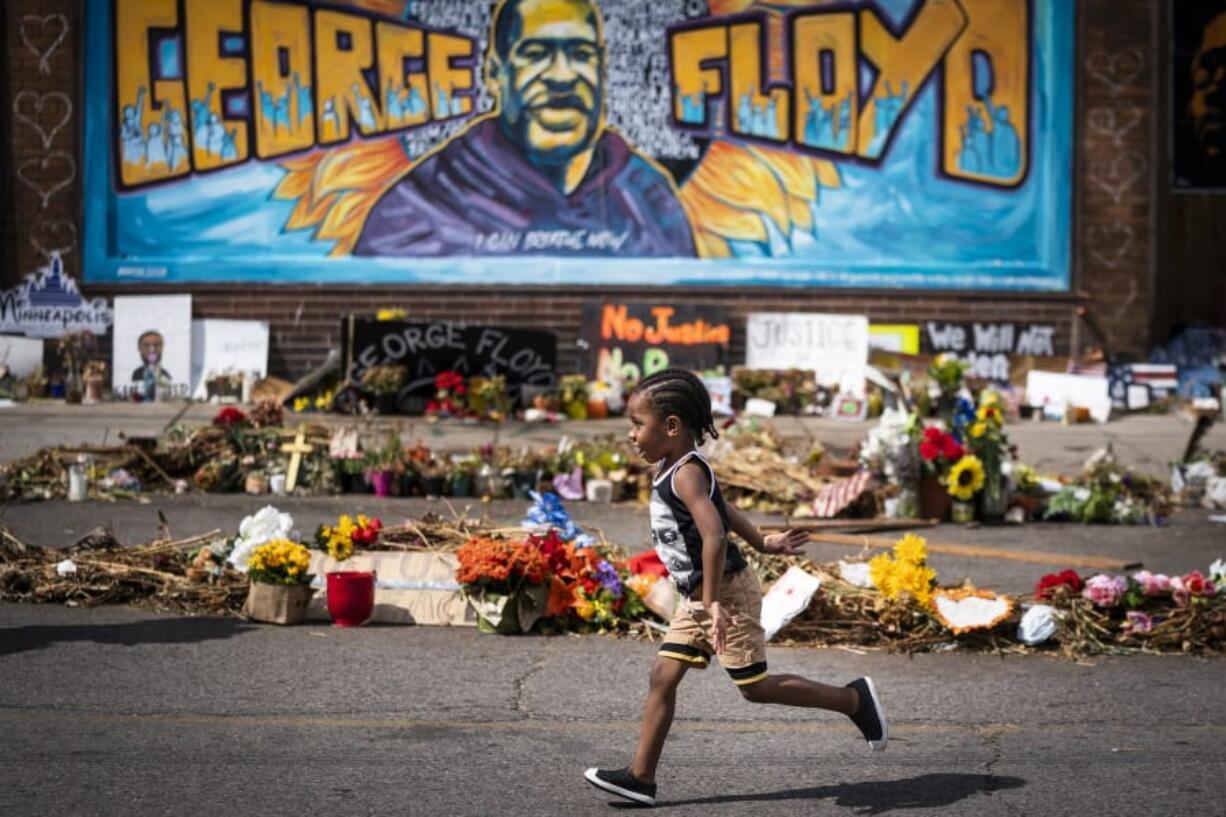 FILE - In this June 25, 2020 file photo, Carter Sims, 3, of Pine Island, Minn., runs past a mural at the George Floyd memorial outside Cup Foods in Minneapolis.  A stretch of a Minneapolis street that includes the place where Floyd was killed will soon be named in his honor.  The City Council approved the naming Friday, Sept. 18, and Mayor Jacob Frey&#039;s office said he would likely sign off on it as well.